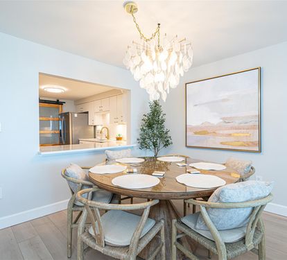 Gather around your elegant dining table under soft chandelier light, with the modern kitchen just steps away for easy entertaining.