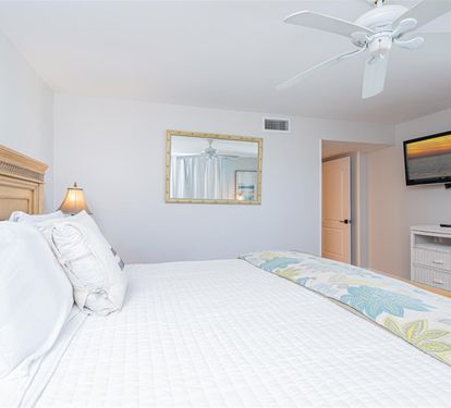 Sink into plush white linens and drift off as your ceiling fan creates a gentle breeze in this serene bedroom retreat.