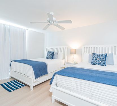 Unwind in your coastal-inspired twin bedroom, where crisp white linens meet ocean-blue accents for a peaceful night's rest.