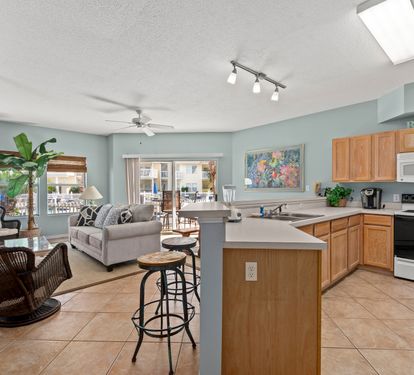 Your spacious open-concept living awaits, where coastal blue walls meet warm wood accents and natural light floods through the skylight above.