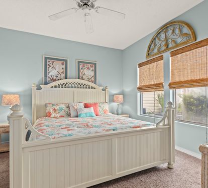 Drift off in your peaceful bedroom sanctuary with coastal charm, soft blue walls, and bamboo blinds filtering gentle light.