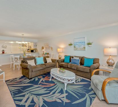 Relax in your bright coastal living room with comfy sofas, tropical decor, and an open kitchen perfect for vacation meals.