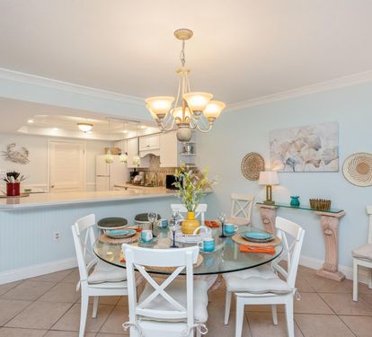 Gather around this elegant glass dining table for memorable meals together, surrounded by coastal charm and open kitchen convenience.