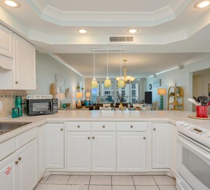 Your fully equipped kitchen features white cabinetry, modern appliances, and an open design connecting to your bright living space.
