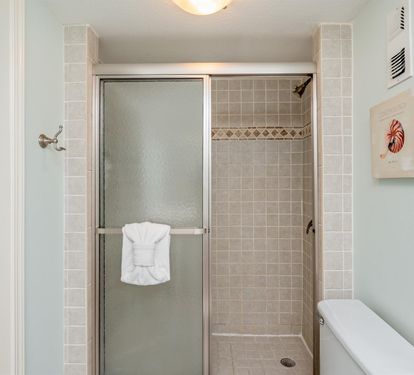 Step into your pristine tiled shower with elegant decorative borders and fresh towels waiting for your arrival.