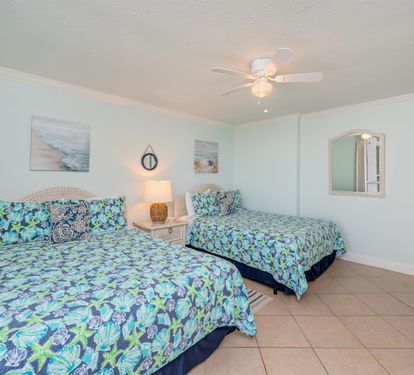 Rest easy in your bright twin bedroom with tropical bedding, gentle ceiling fan, and coastal artwork creating a peaceful retreat.