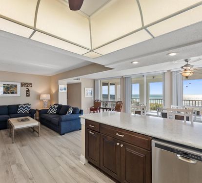 Relax in your open-concept living space with stunning ocean views through floor-to-ceiling windows, complete kitchen, and cozy seating area.