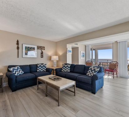 Sink into plush navy sofas and let the ocean breeze flow through your private balcony doors in this bright, coastal living space.