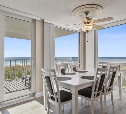 Your coastal dining area frames stunning ocean views through floor-to-ceiling windows, with a ceiling fan keeping you comfortable during beachside meals.