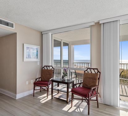 Your comfortable seating area bathes in sunlight with stunning ocean views through floor-to-ceiling windows, perfect for morning coffee or evening relaxation.