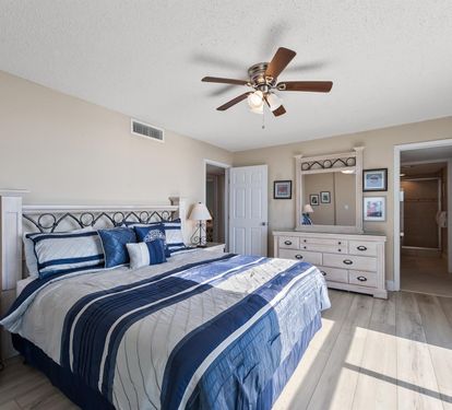 Drift off peacefully in your coastal bedroom featuring crisp blue linens, warm wood floors, and gentle ceiling fan breezes.