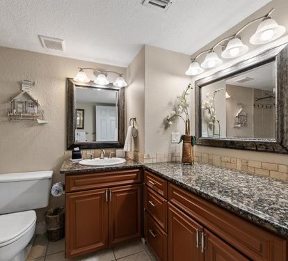 Pamper yourself in this elegantly appointed bathroom featuring granite countertops, rich wood cabinetry, and a spacious walk-in shower.
