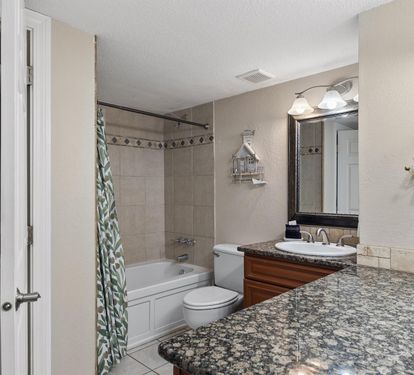 Pamper yourself in this spa-like bathroom featuring granite countertops, elegant vanity lighting, and a relaxing soaking tub.