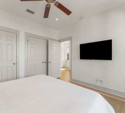 Bright, airy bedroom with wall-mounted TV and ample closet space