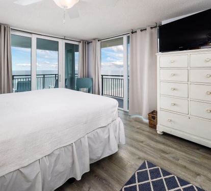 Master Bedroom with King Bed and 2 Floor to Ceiling Sliding Glass Doors to Balcony