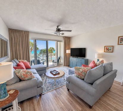 Living room with updated seating, a TV, and direct balcony access with Gulf views.