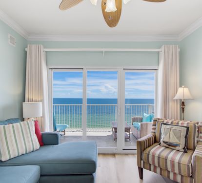 Bright Gulf-front living room with direct balcony access and a TV.