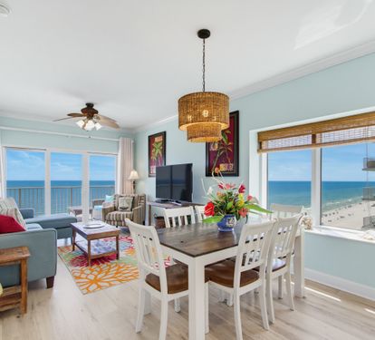 Open living and dining area with panoramic Gulf views and a TV.