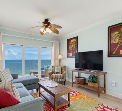 Living-area seating beside floor-to-ceiling Gulf views and a TV.