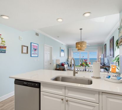 Kitchen sink and breakfast bar overlooking the dining area and living room with a TV.