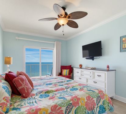 Primary king bedroom with Gulf views, balcony access, and a wall-mounted TV.